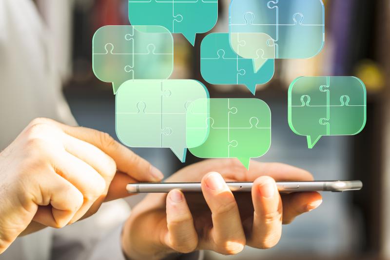 Hand mit Handy, darüber Sprechblasen aus Puzzleteilen, © AdobeStock